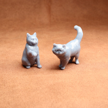 Two small gray cat figurines on a brown surface