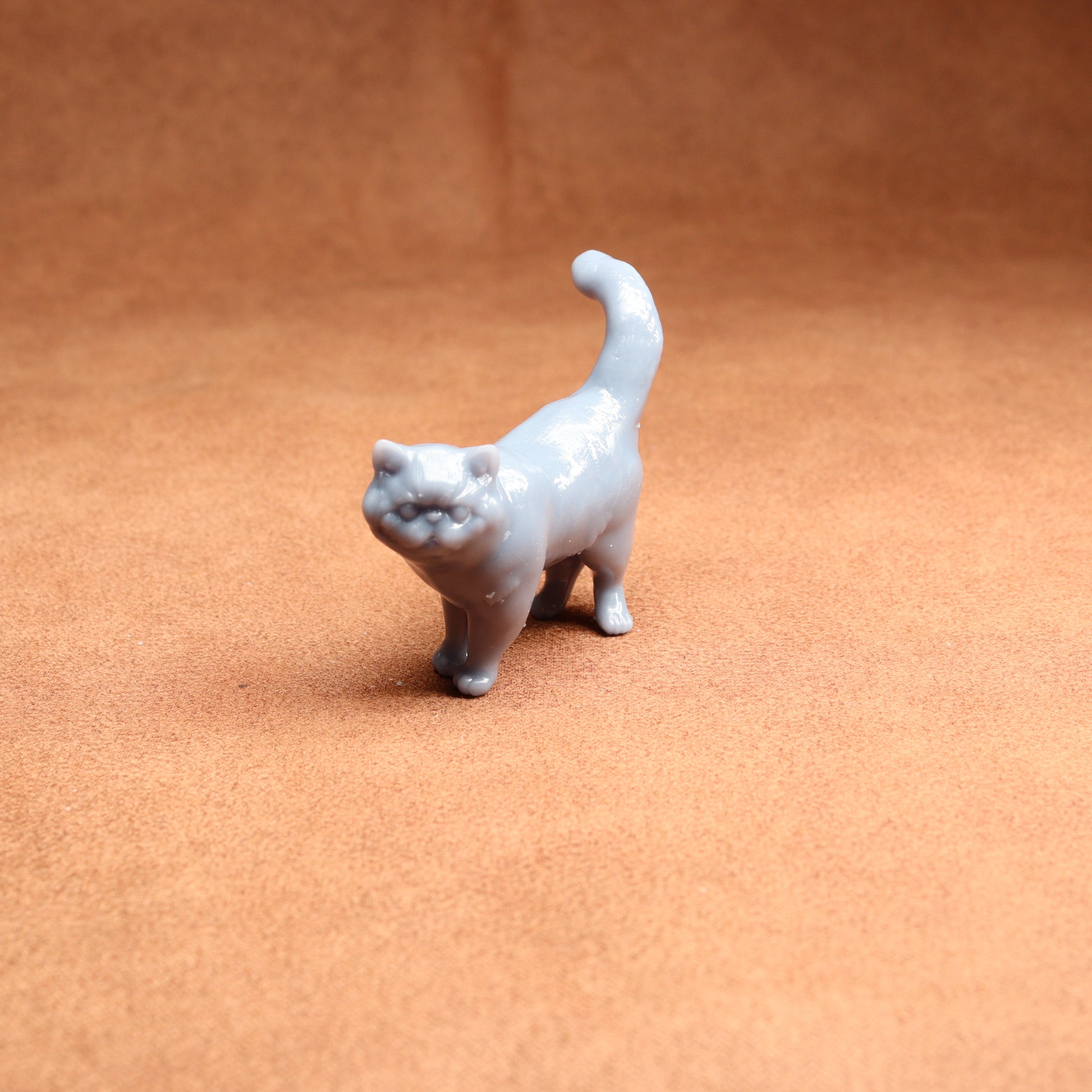 Small white cat figurine on a brown surface
