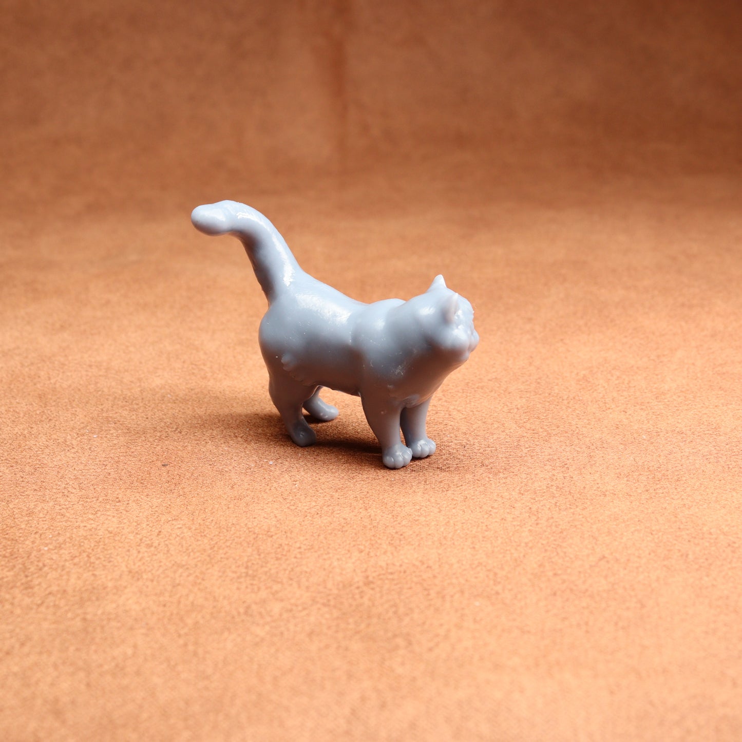 Small gray cat figurine on a brown surface