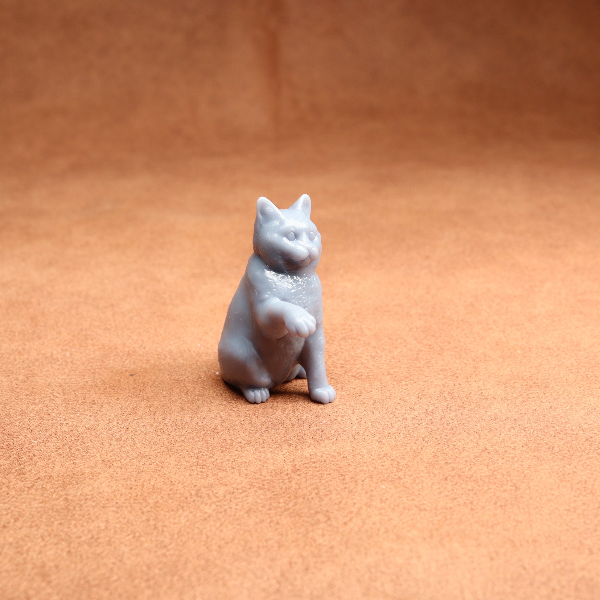 Gray cat figurine on a brown surface