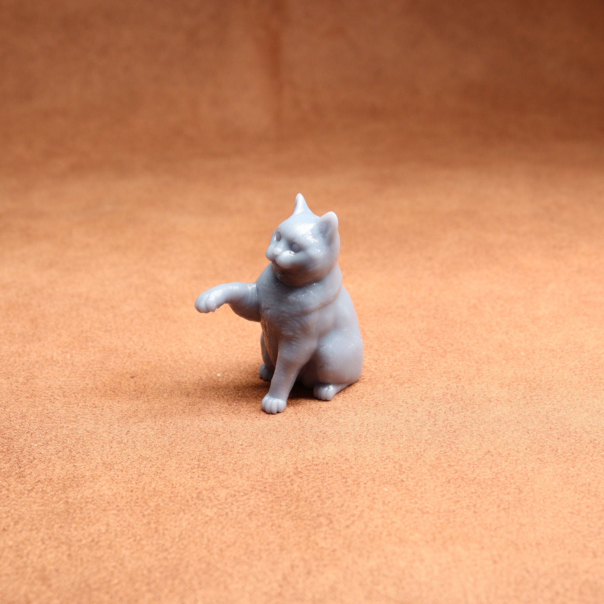 Small gray cat figurine on a brown surface