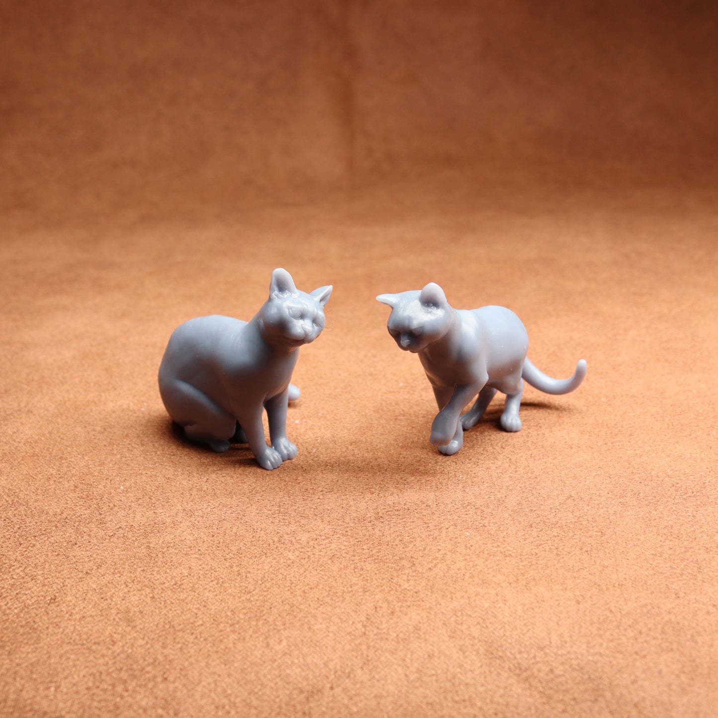 pair of grey cat figures on a brown background