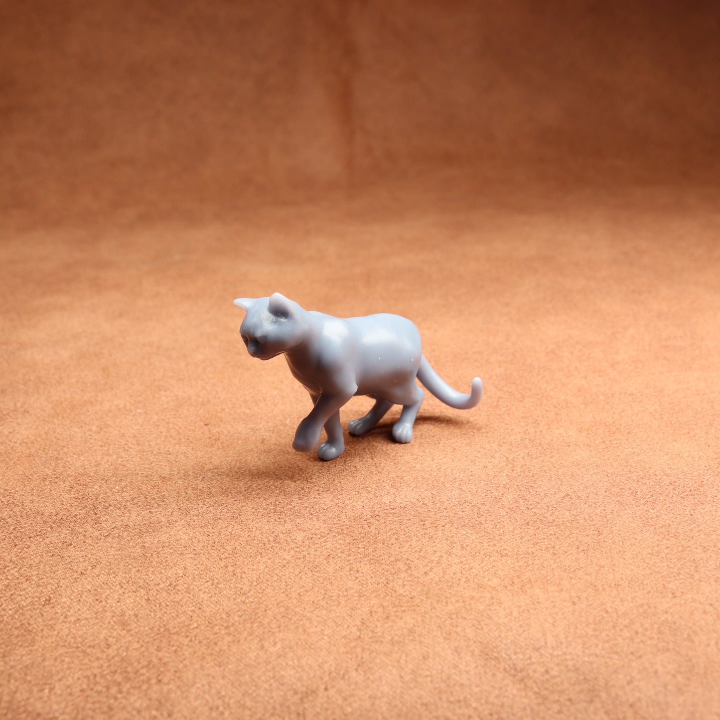Gray toy cat figure on a brown surface