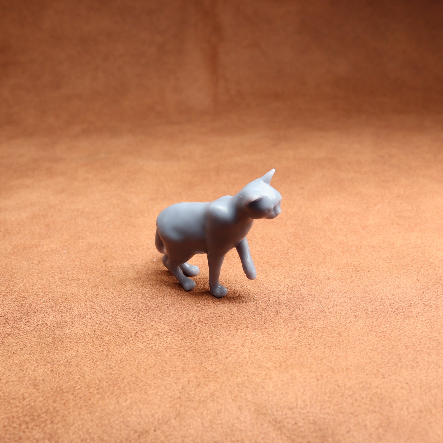 Gray cat figurine on a brown surface
