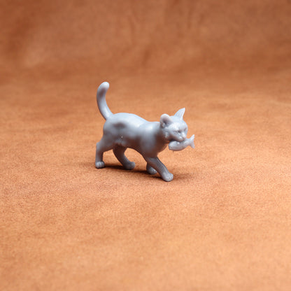 Gray cat figurine holding a fish on a brown surface