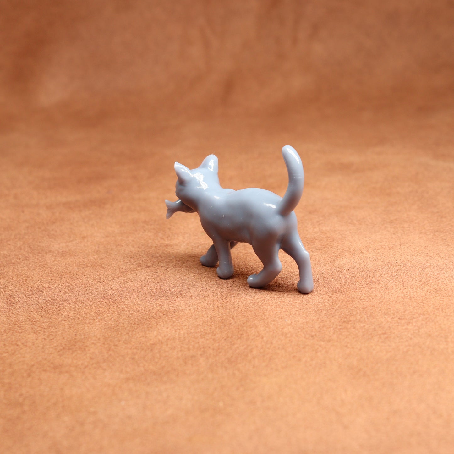 Small gray cat figurine on a brown surface