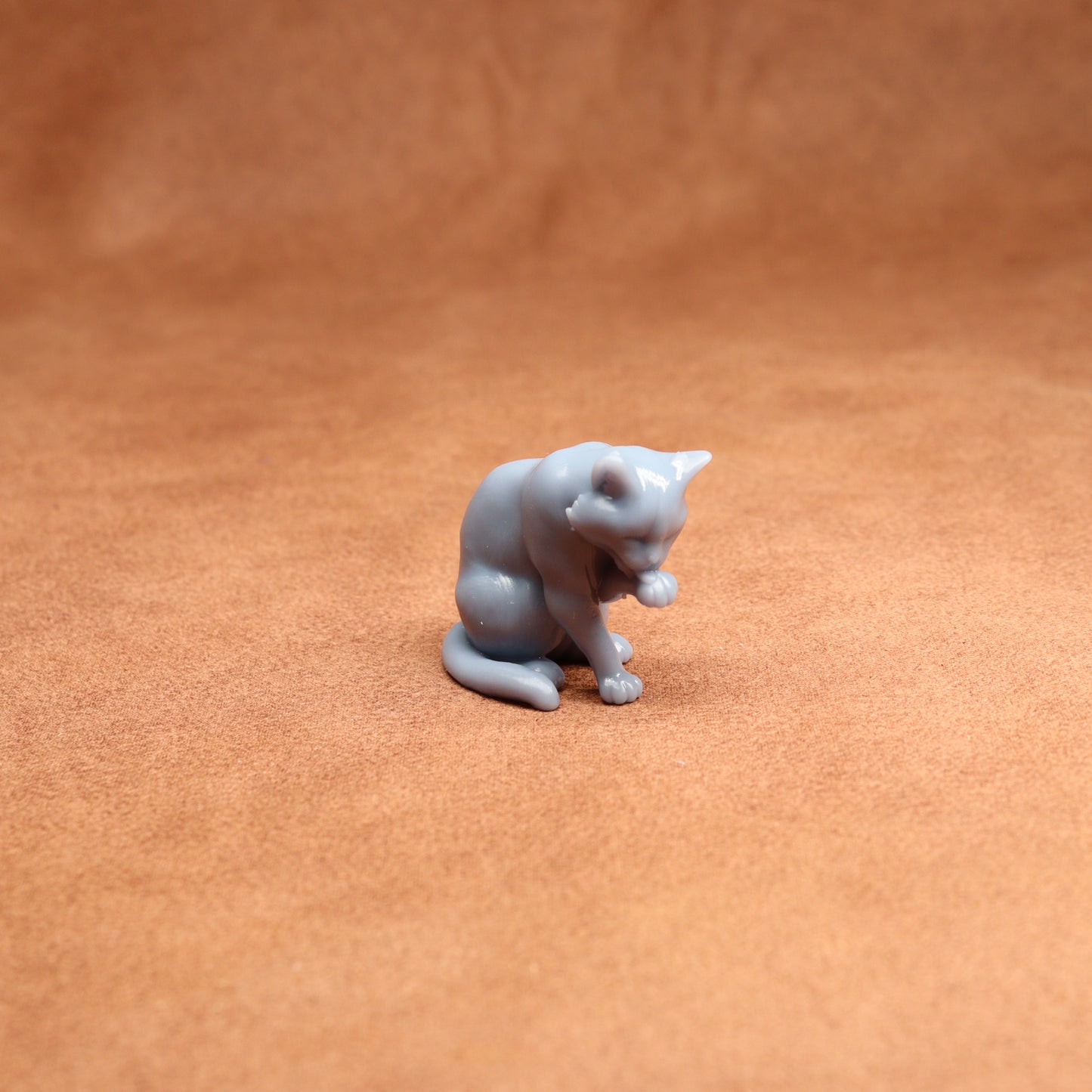 Small gray cat figurine on a brown surface