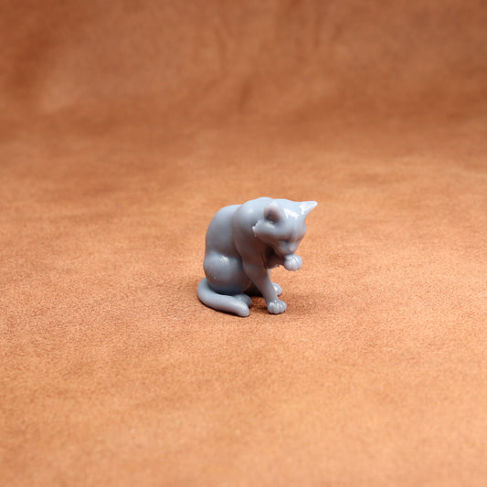 Small gray cat figurine on a brown surface