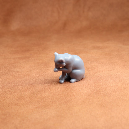 Small gray cat figurine on a brown surface