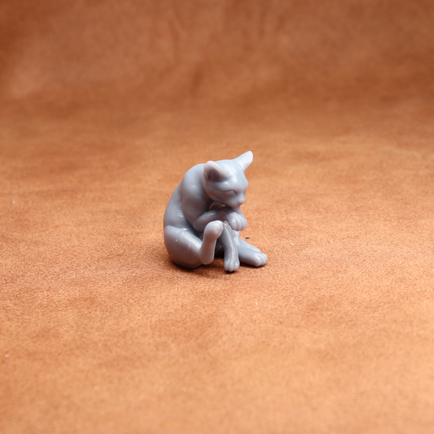 Small gray cat figurine on a brown surface