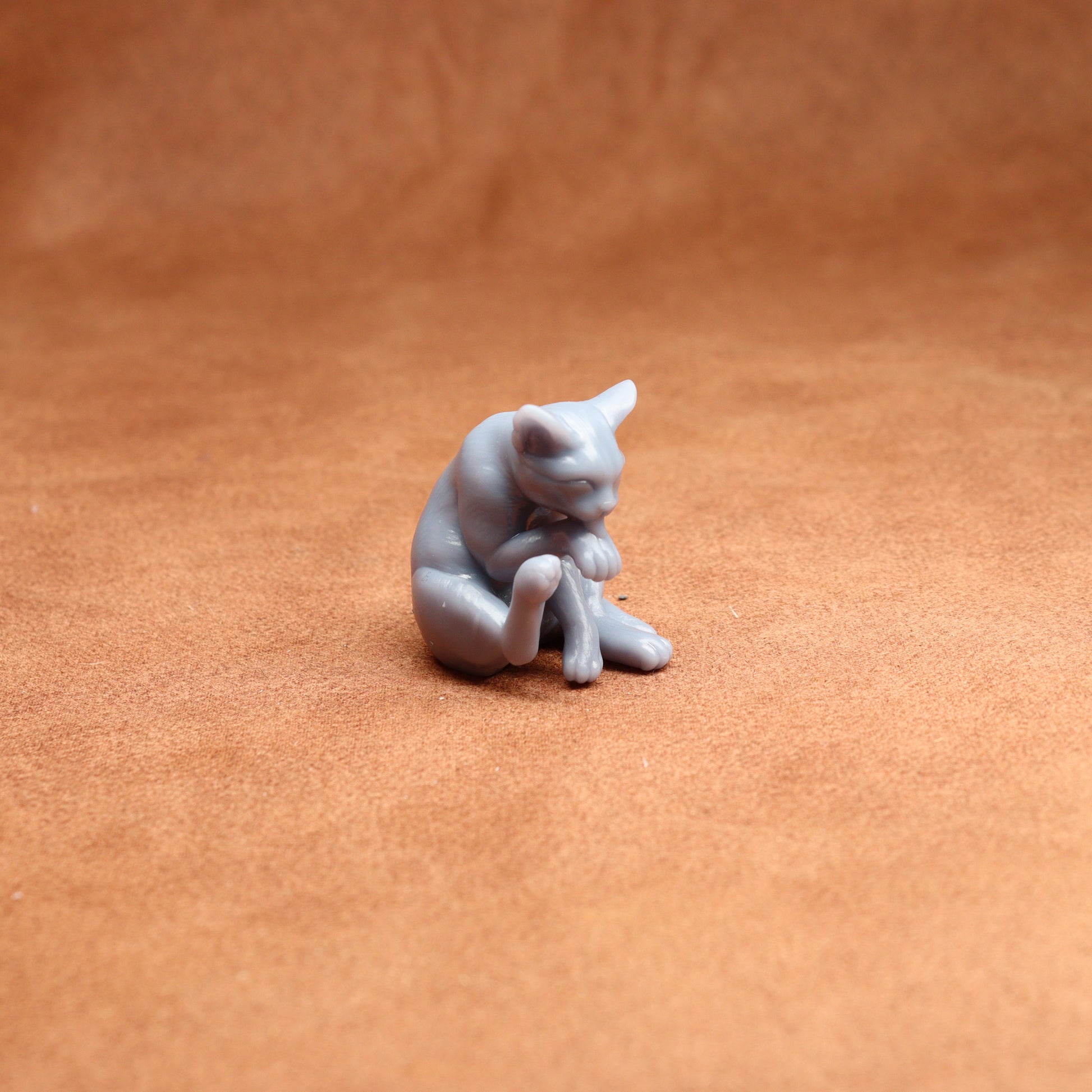 Small gray cat figurine on a brown surface