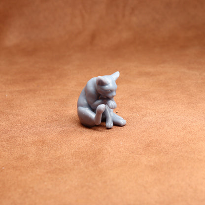 Small gray cat figurine on a brown surface