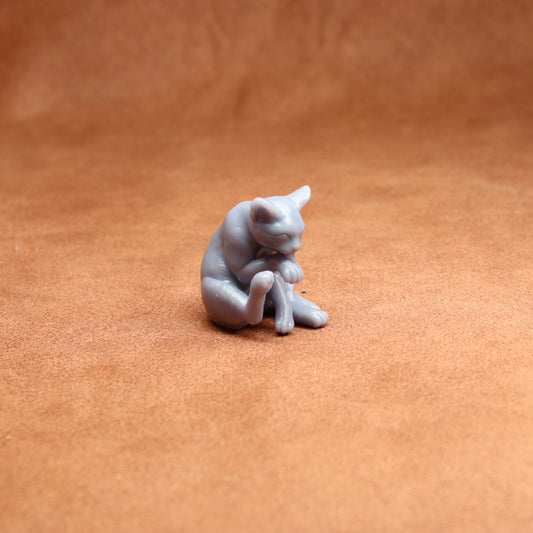 Small gray cat figurine on a brown surface