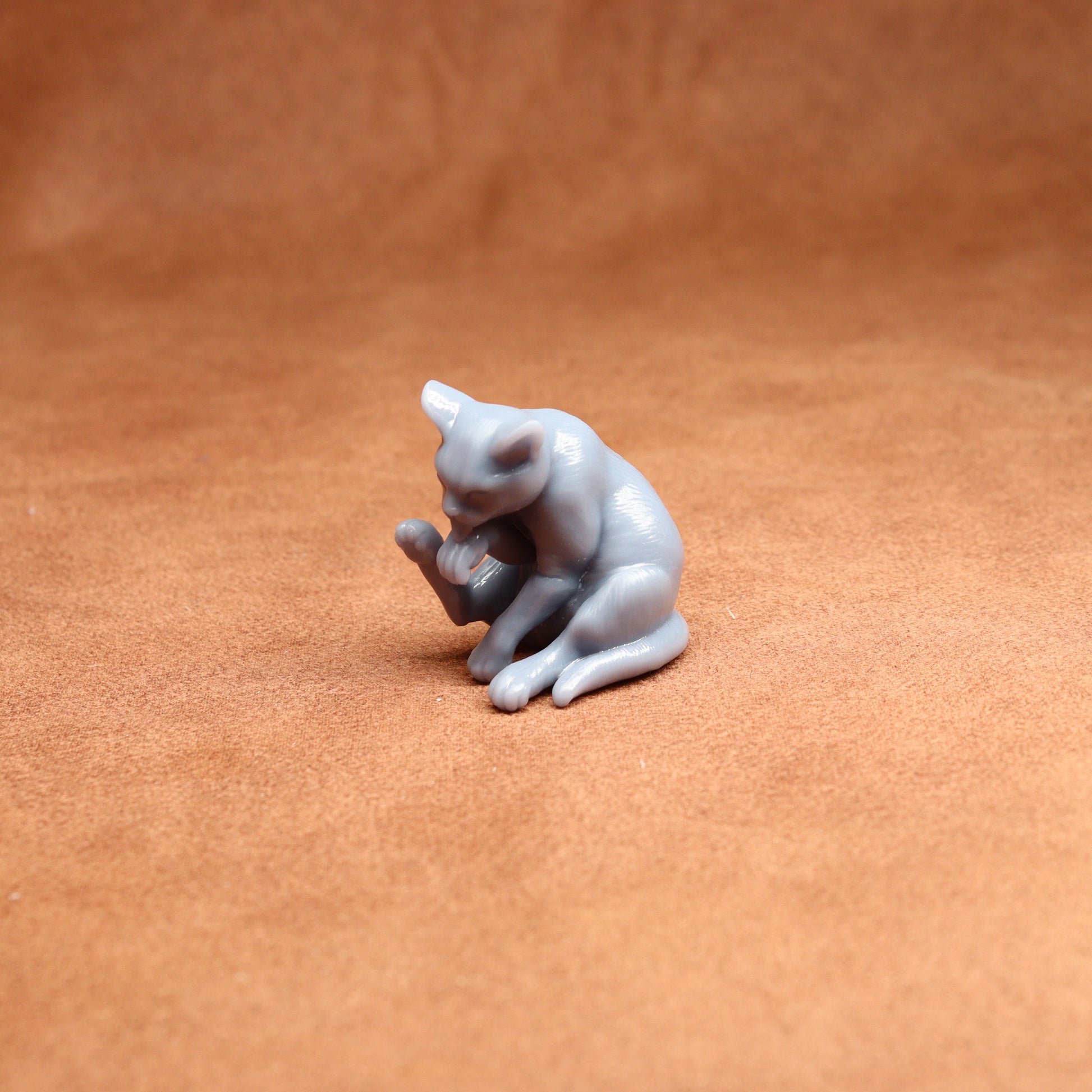 Small gray cat figurine on a brown surface