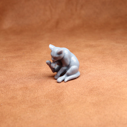 Small gray cat figurine on a brown surface