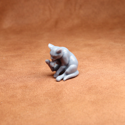 Small gray cat figurine on a brown surface