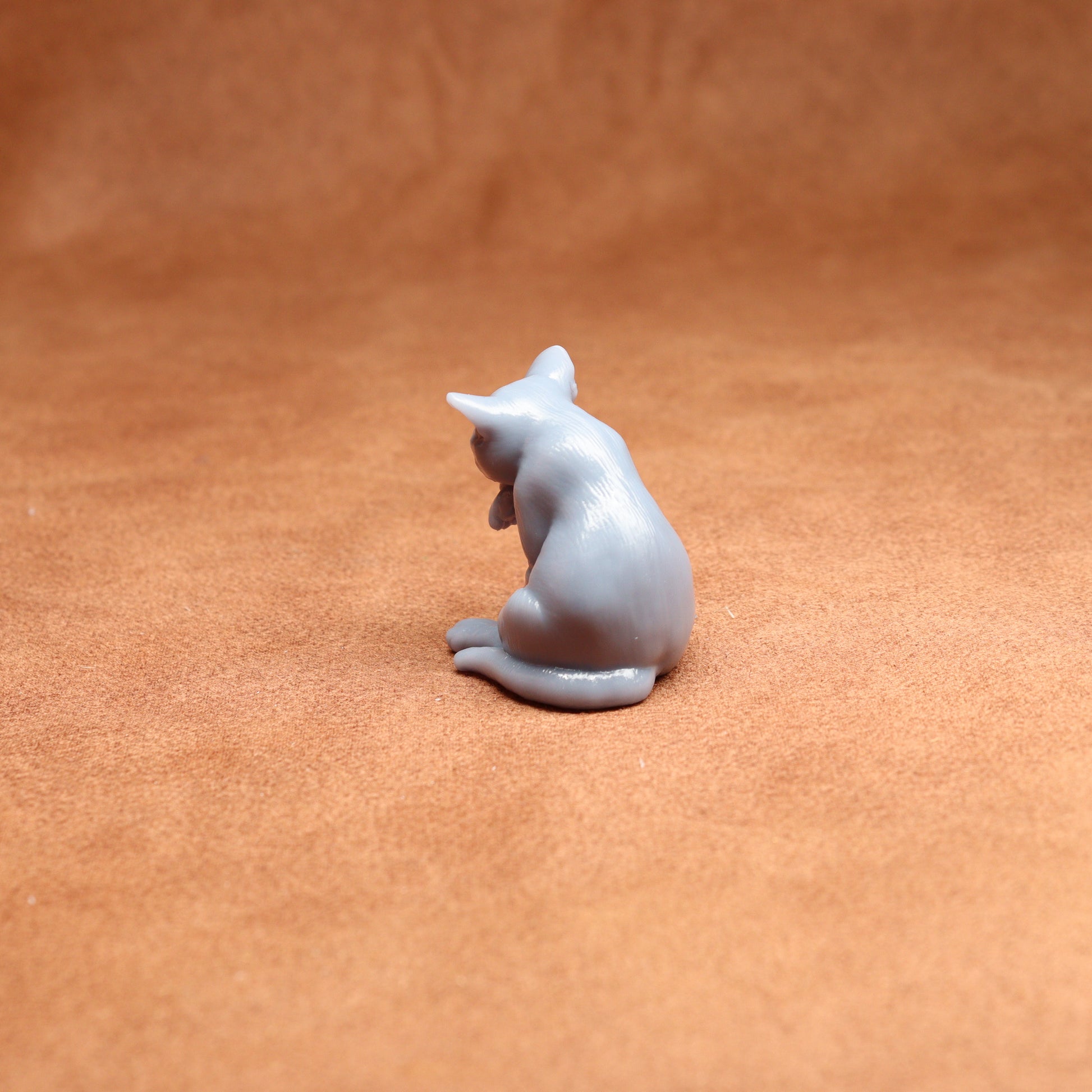 White ceramic cat figurine on a brown leather surface