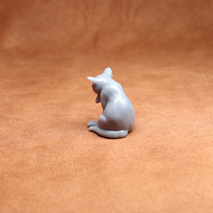 White ceramic cat figurine on a brown leather surface