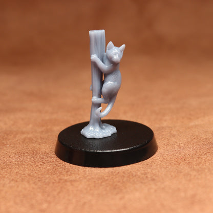 grey cat resin miniature on a black base on a brown background.