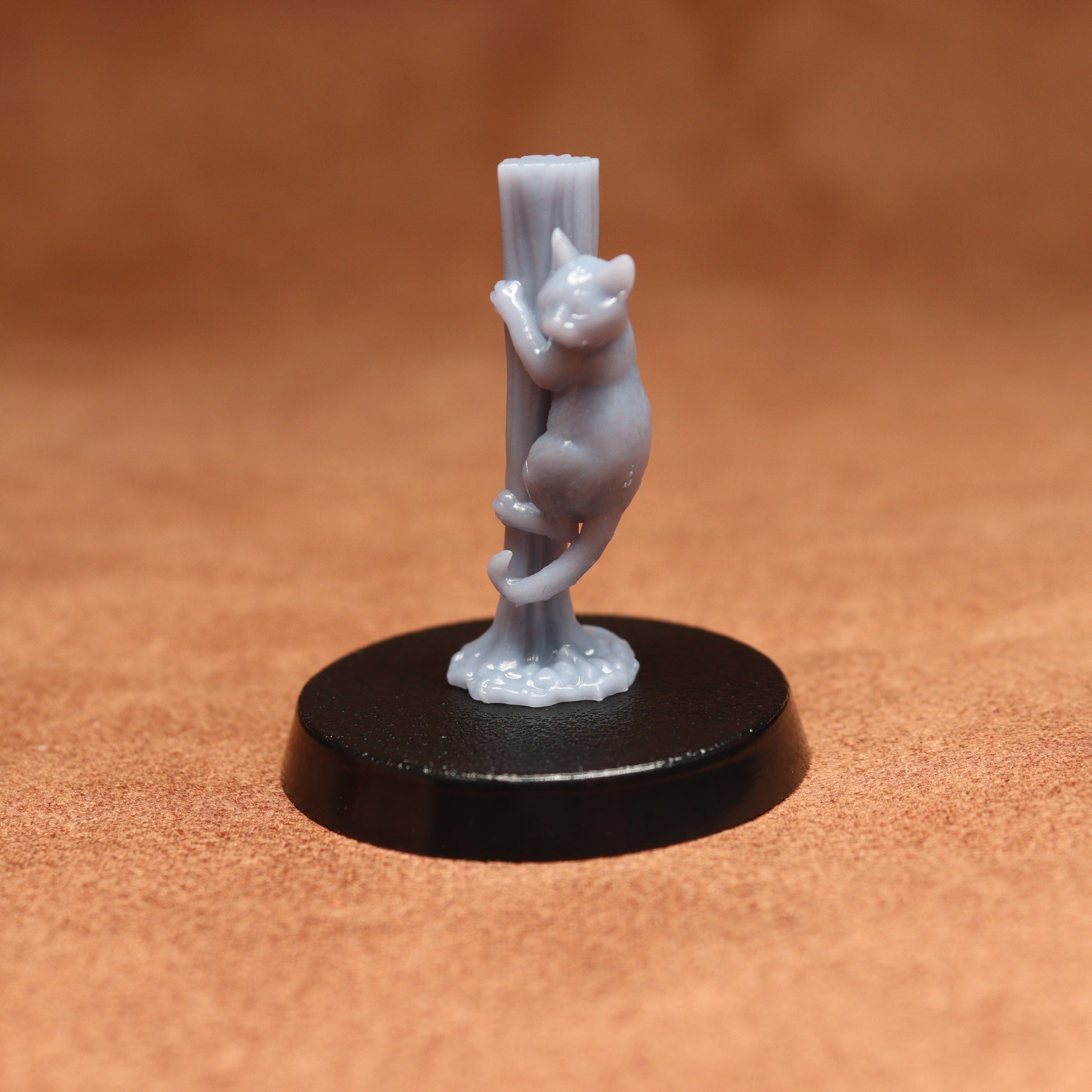 grey cat resin miniature on a black base on a brown background.