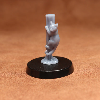 grey cat resin miniature on a black base on a brown background.