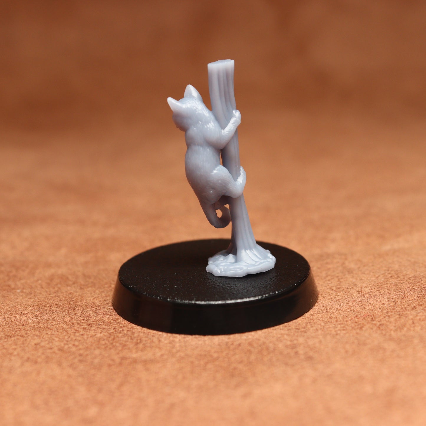 grey cat resin miniature on a black base on a brown background.