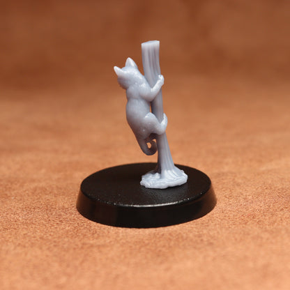 grey cat resin miniature on a black base on a brown background.