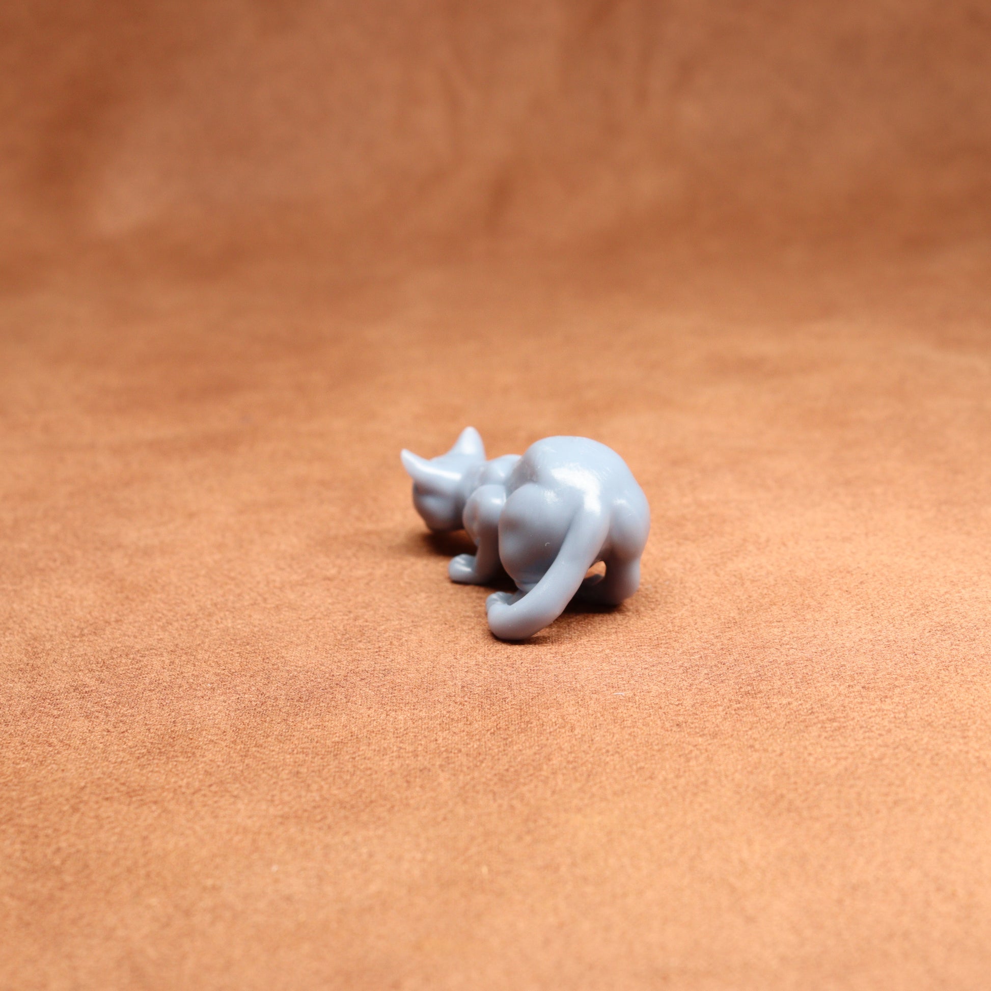 Small white resin cat figurine on a brown leather surface