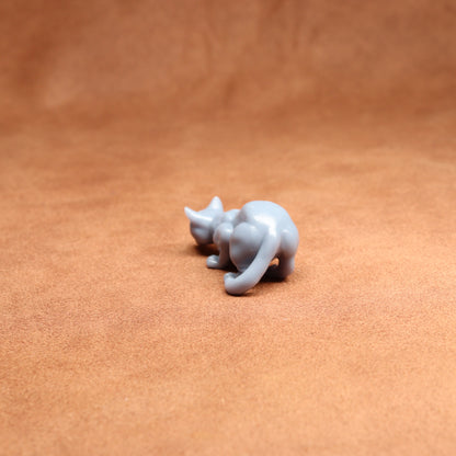 Small white resin cat figurine on a brown leather surface