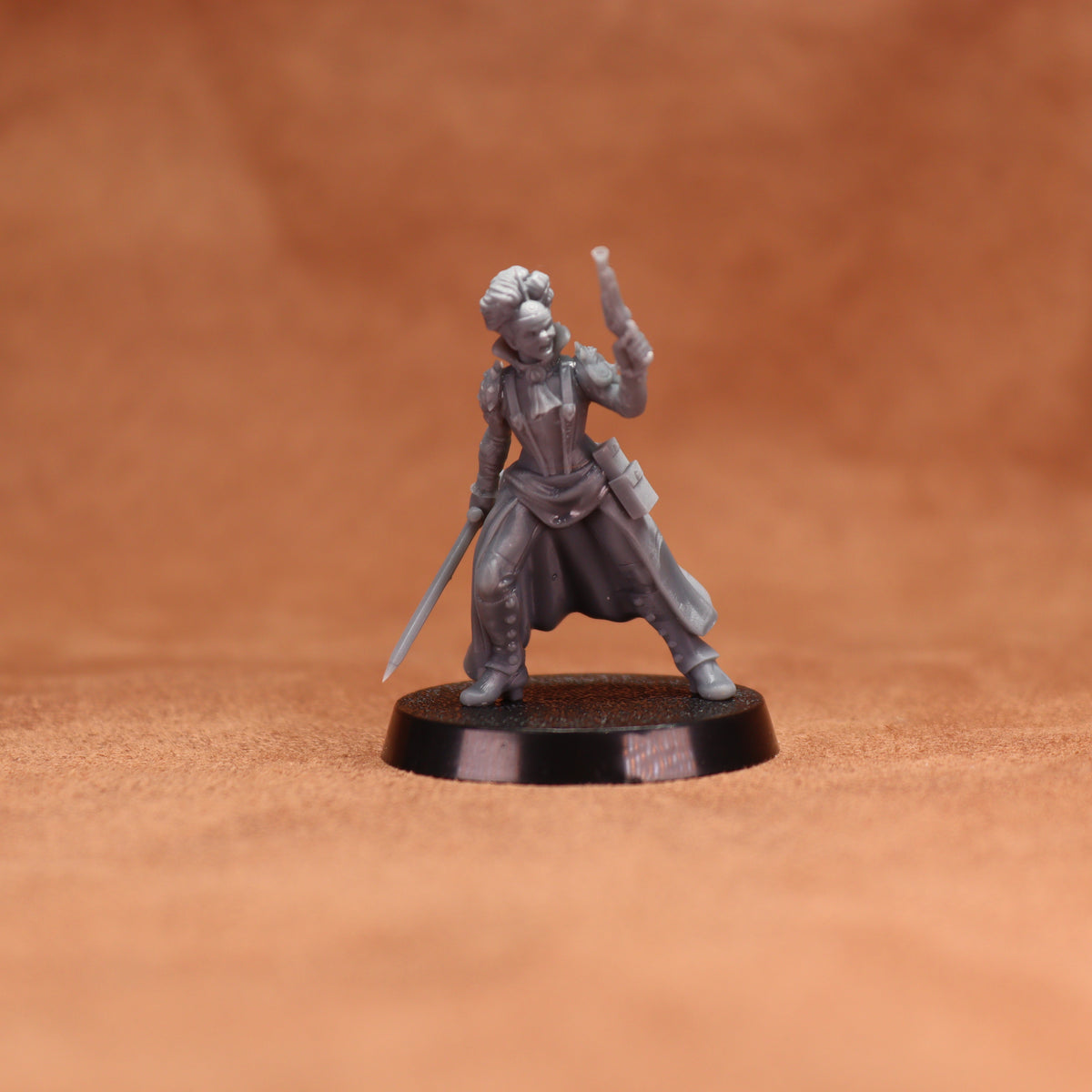 An unpainted gray fantasy miniature figurine of a warrior holding a sword and a cup, standing on a round black base against a warm brown textured background.