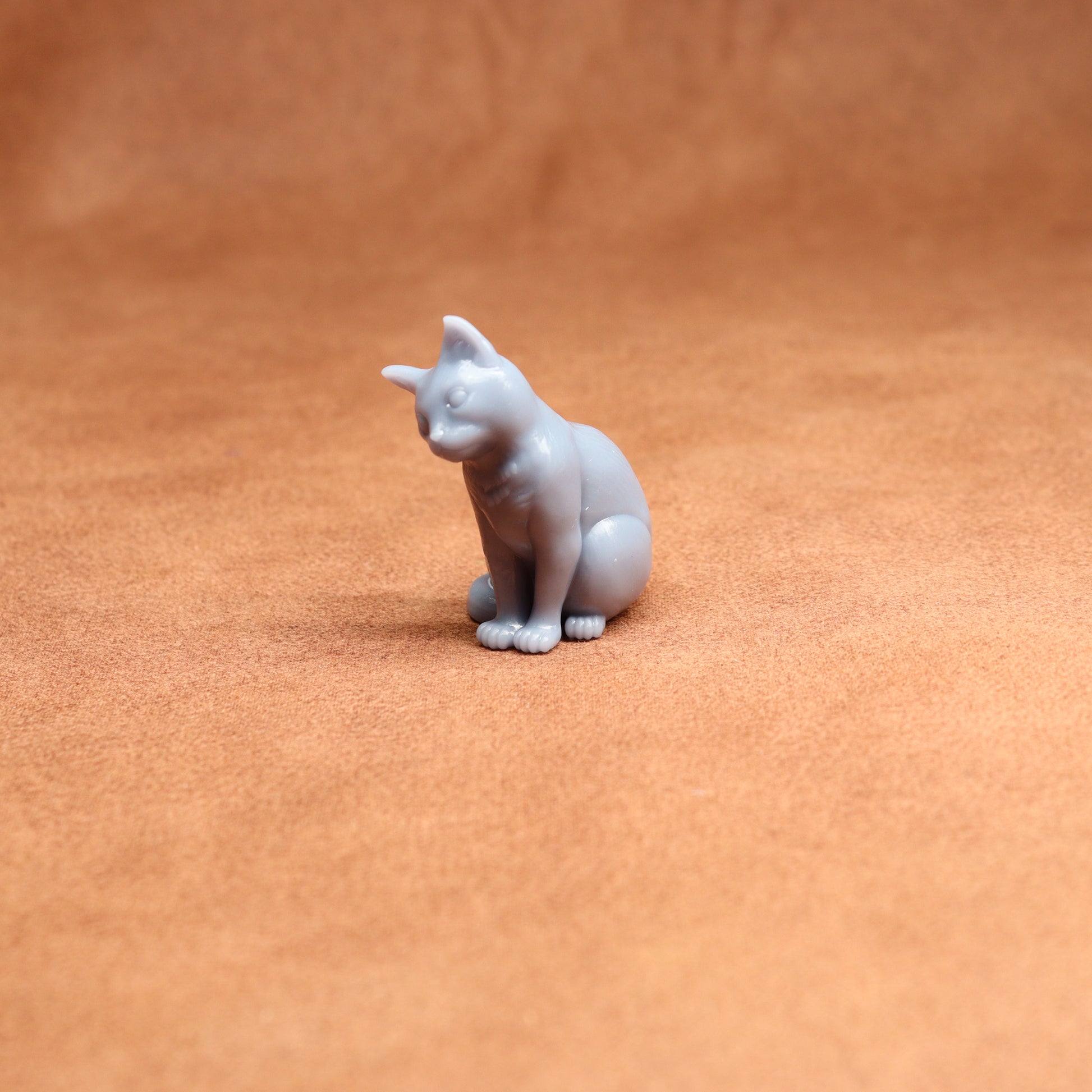 Small white cat figurine on a brown surface
