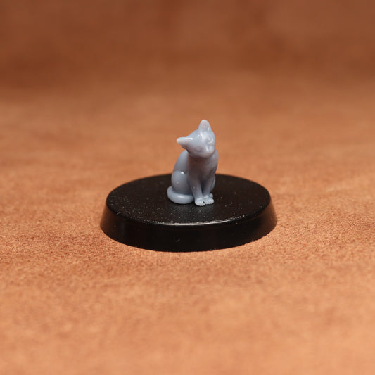 Small white cat figurine on a black round base against a brown background