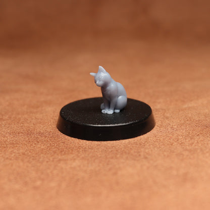 Small gray cat figurine on a black round base against a brown background