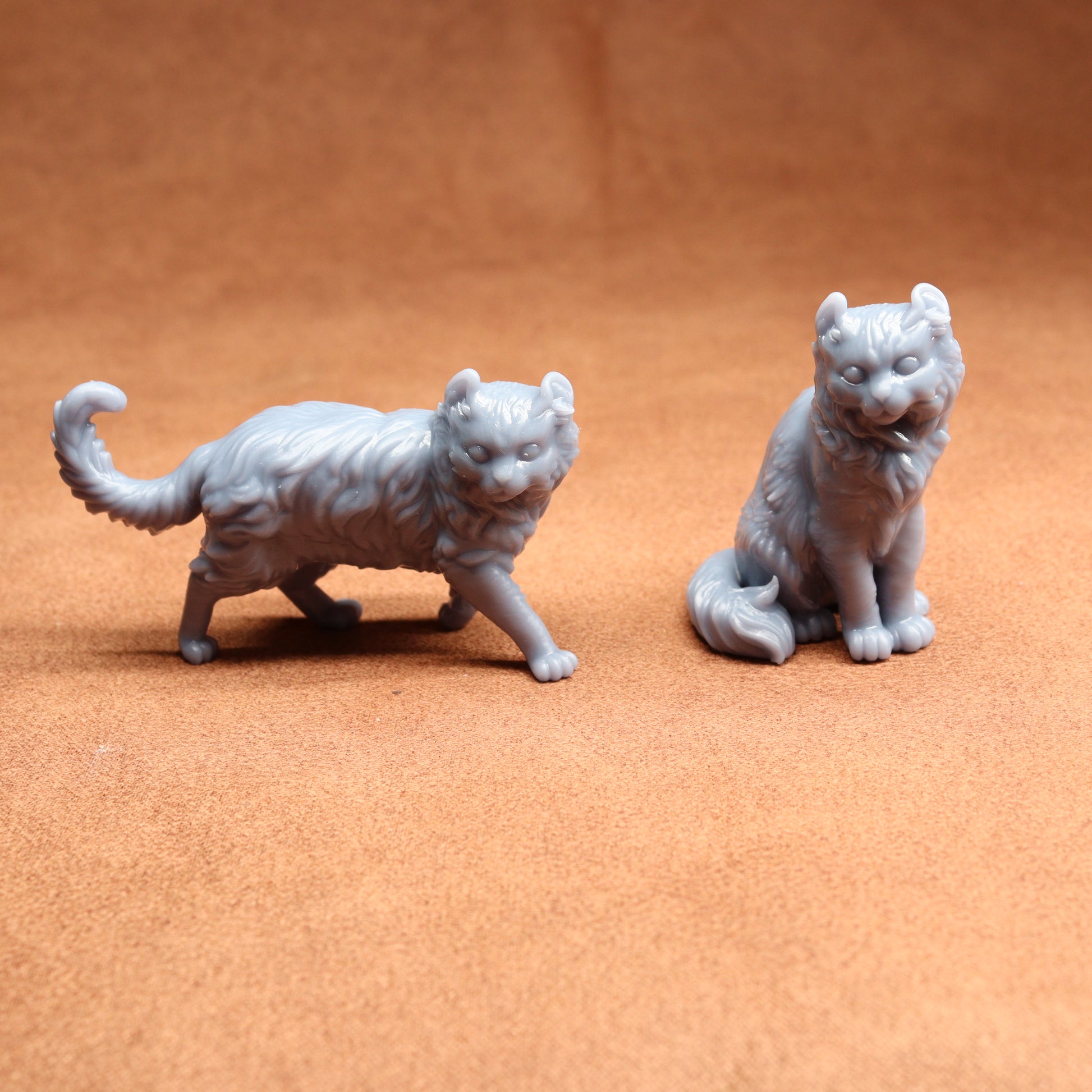 Two gray cat figurines on a brown surface