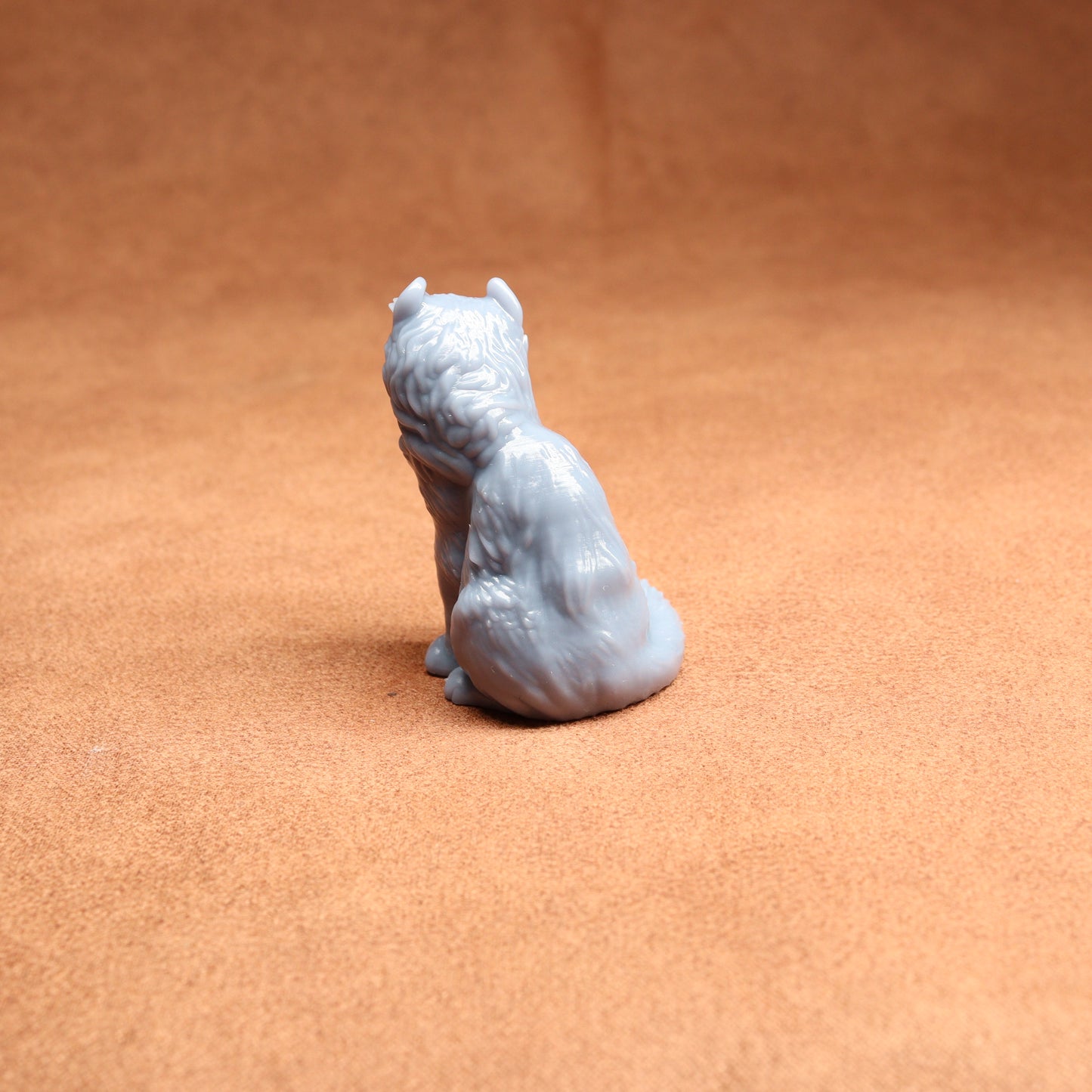 Small gray figurine of a sitting animal on a brown surface