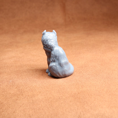 Small gray figurine of a sitting animal on a brown surface