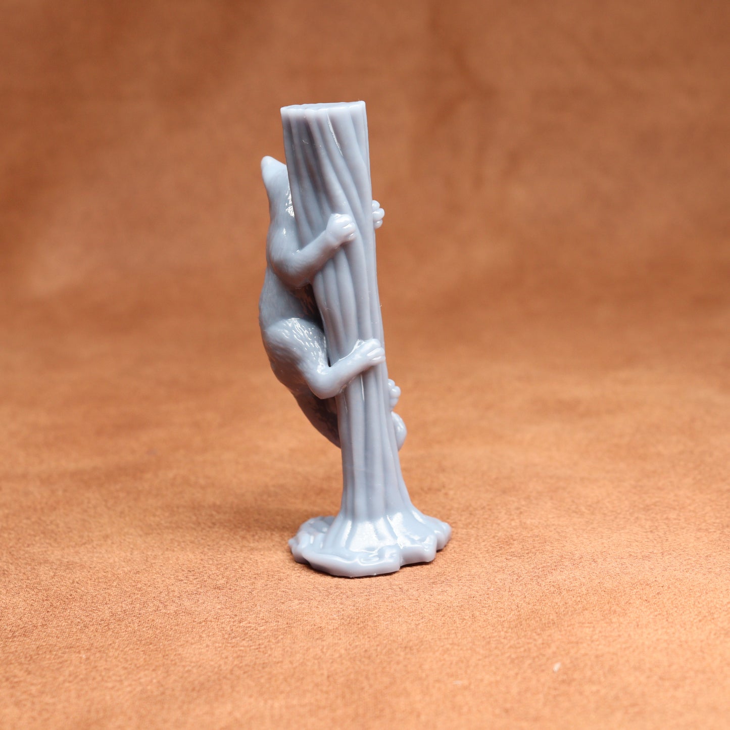 Gray figurine of a hand holding a stick on a brown background