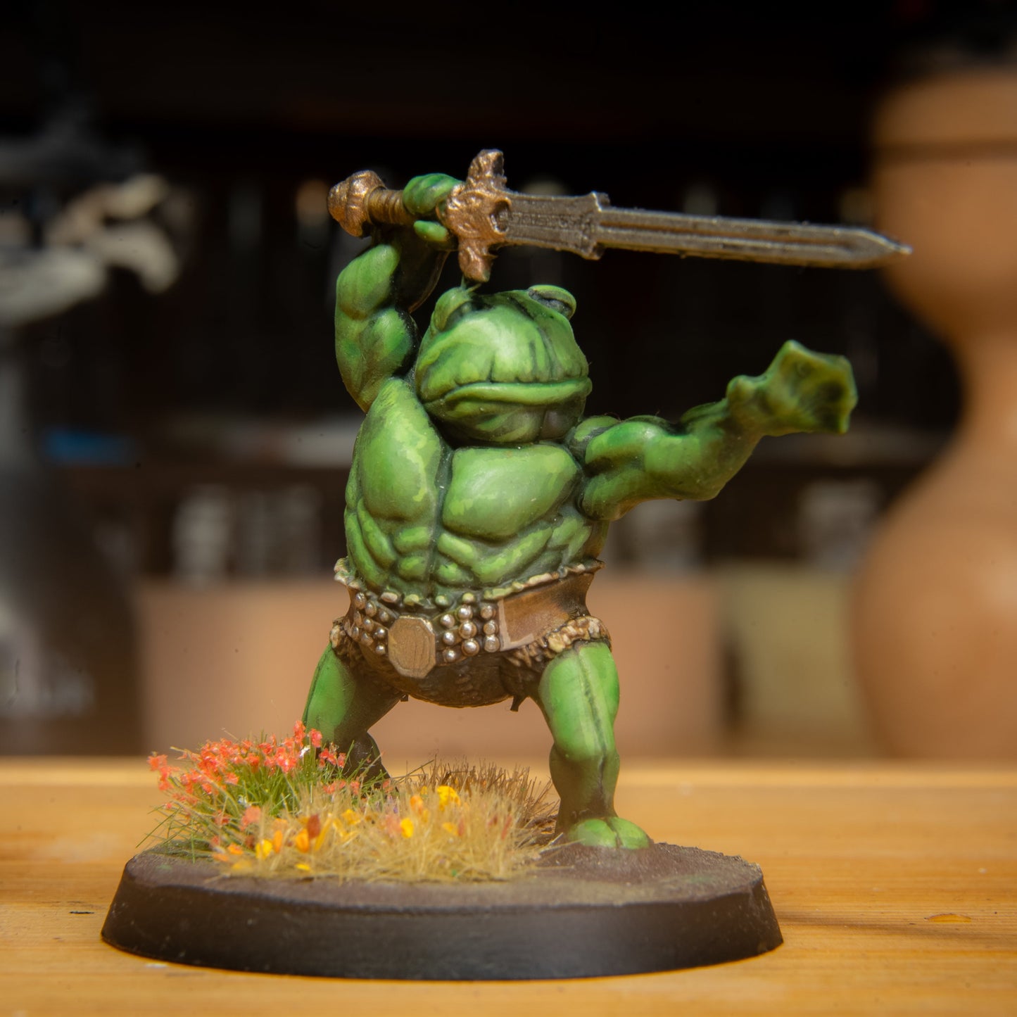 painted frog barbarian miniature on a wooden surface
