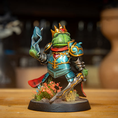painted frog king miniature on a wooden surface