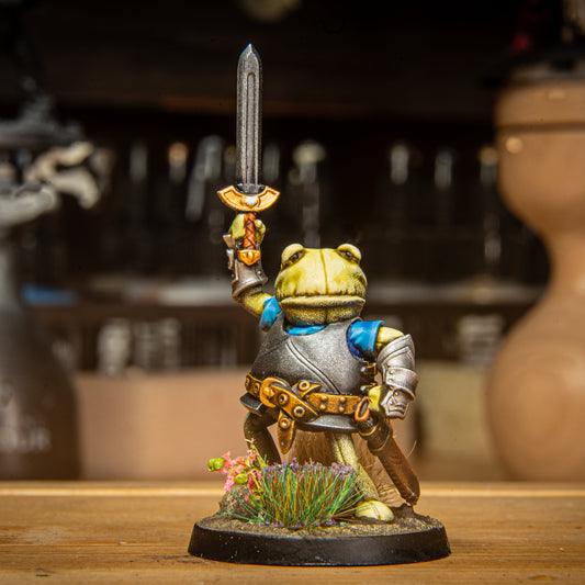 painted frog knight miniature on a wooden surface