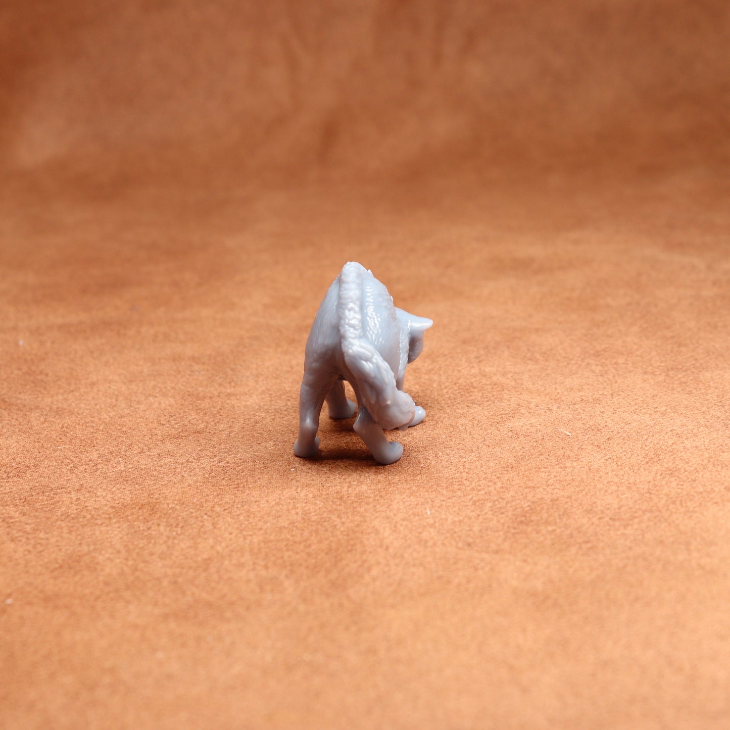 Small white figurine of a cat on a brown surface