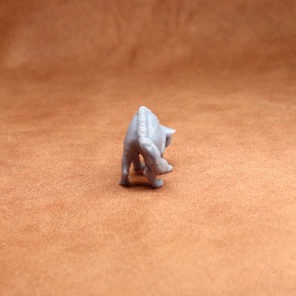 Small white figurine of a cat on a brown surface