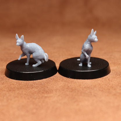 Two miniature cat figurines on black bases against a brown background