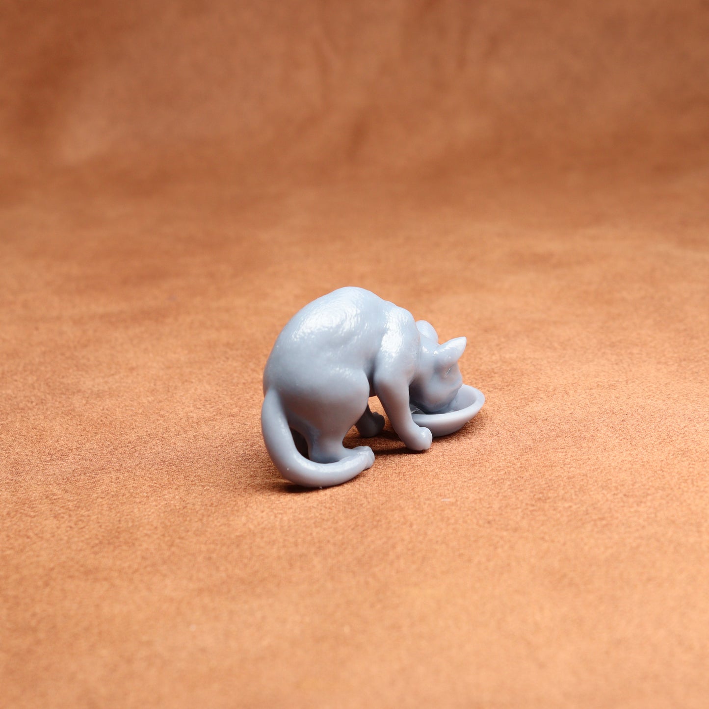 Small white cat figurine on a brown surface