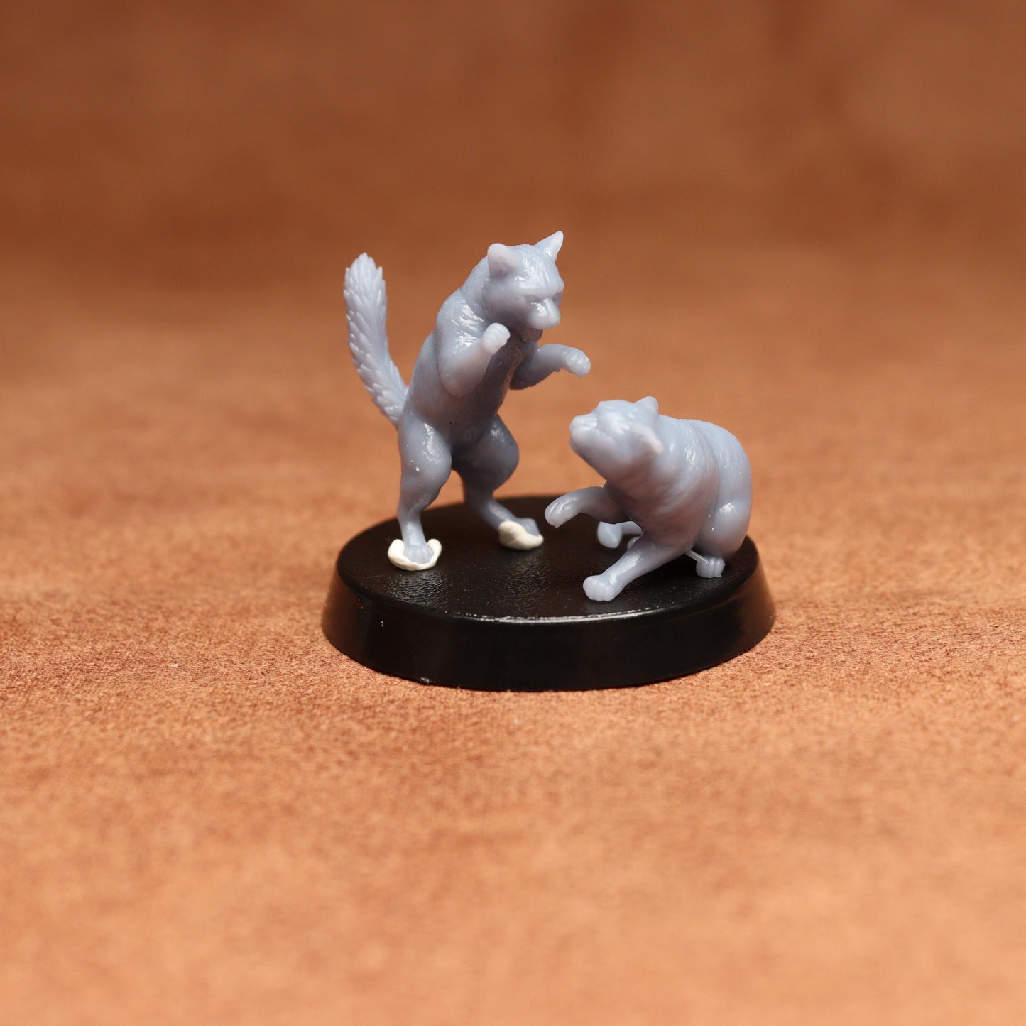 grey resin miniature cat figure on a black base with a brown background