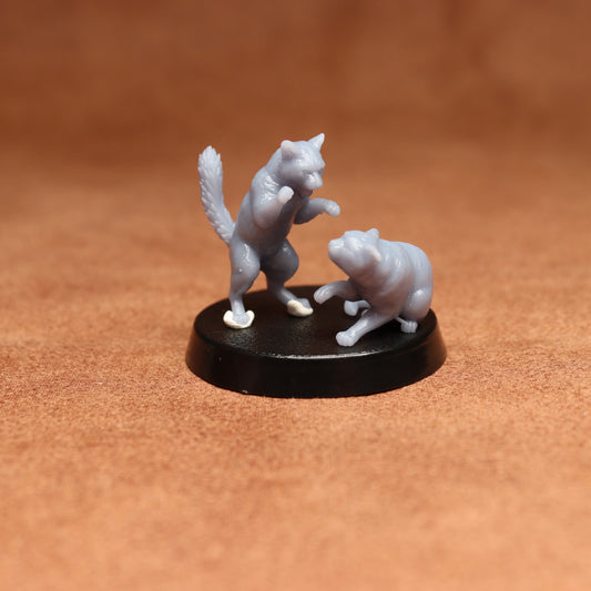 grey resin miniature cat figure on a black base with a brown background