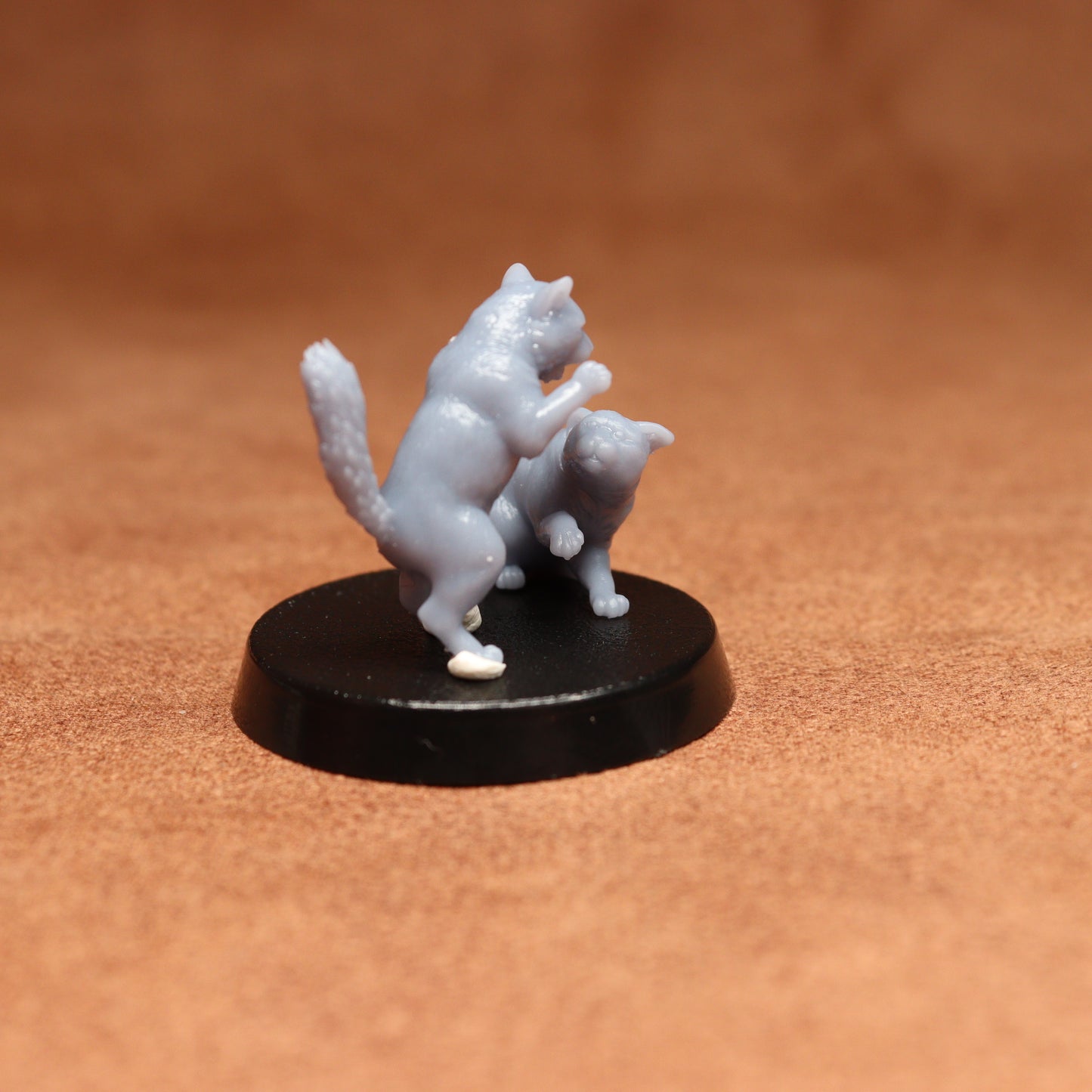grey resin miniature cat figure on a black base with a brown background