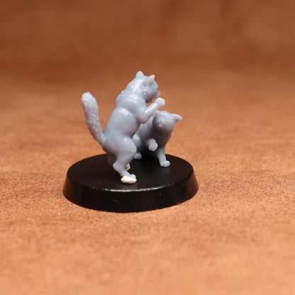 grey resin miniature cat figure on a black base with a brown background