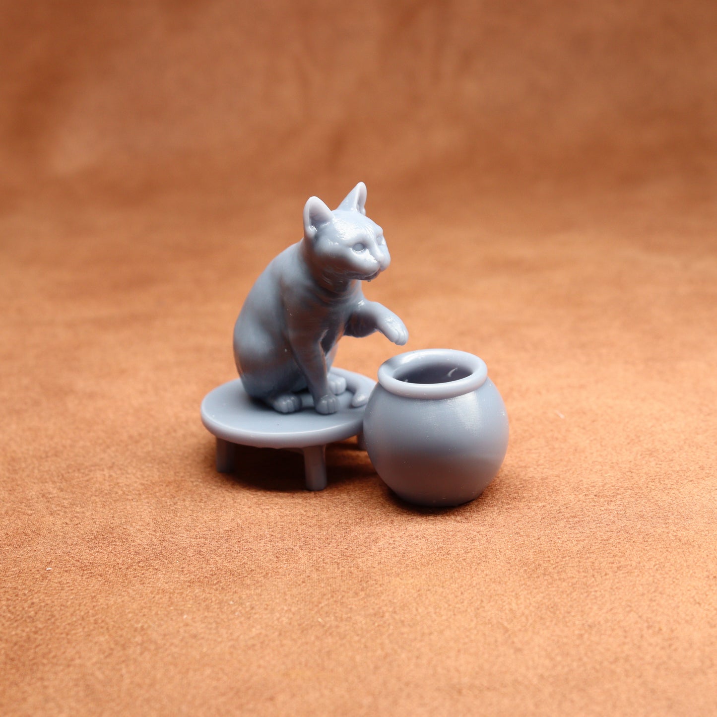 Gray ceramic cat figurine with a small table and pot on a brown background