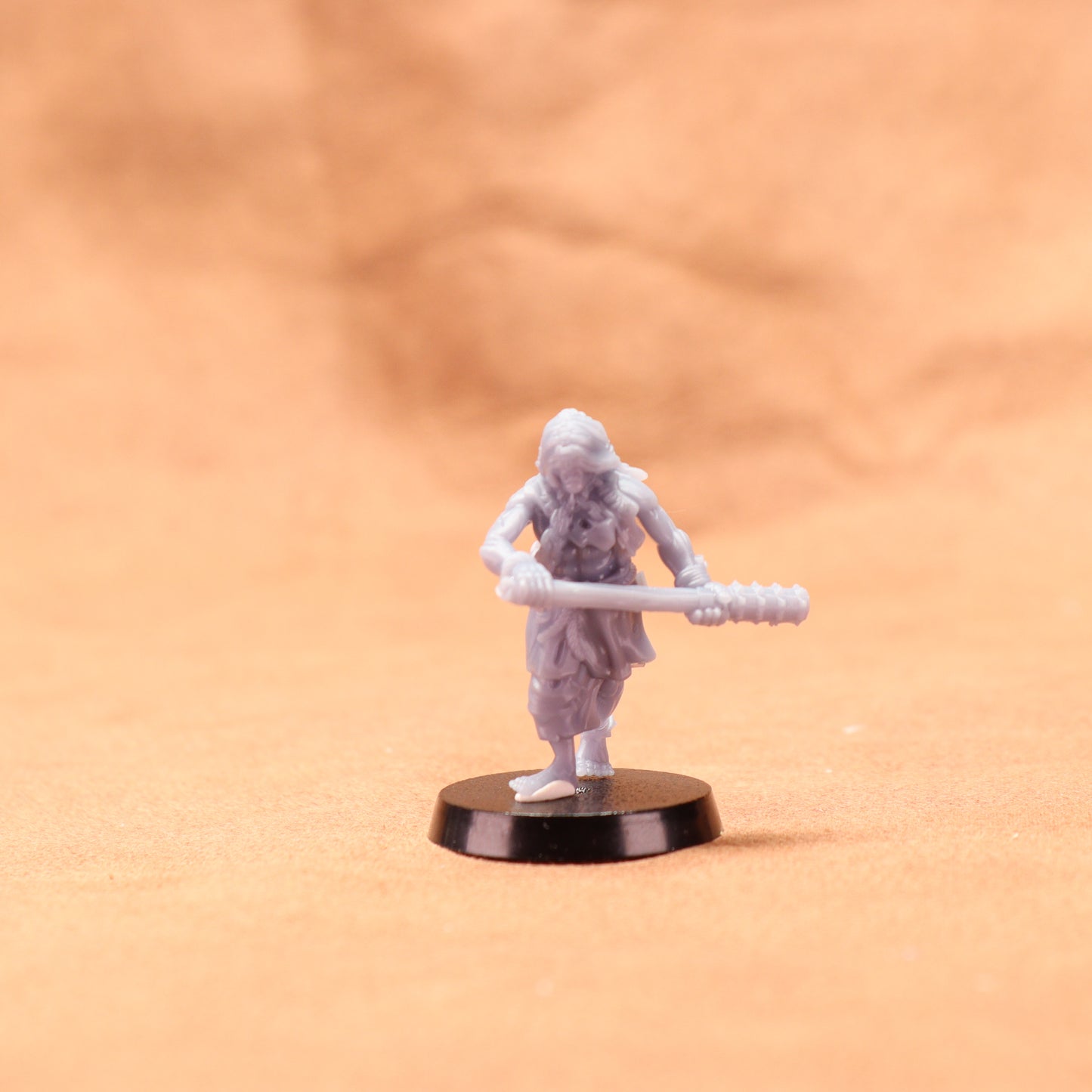 Miniature figurine of a warrior holding a spear on an orange background